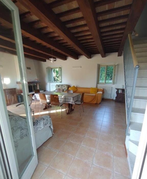 Il soggiorno con travi a vista, tavolo da pranzo e scala